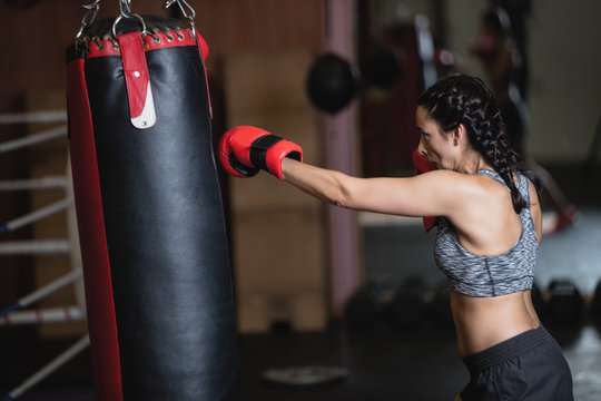 Female boxer practicing boxing with punching bag