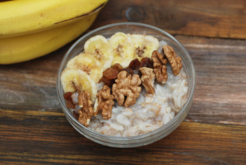 Top view of a Granola Bowl, Muesli with Oats, Nuts and Dried Fruit on Wooden table. Bannana, nuts, fruits. Healthy Breakfast. Diet.