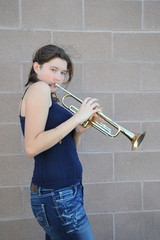 Female jazz trumpet player blowing her horn outside.