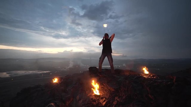 Bright sunset, the man with the fire is on the mountain. Fire-show.