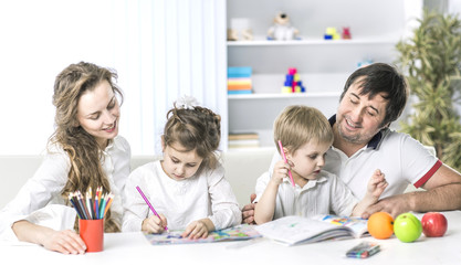 Fototapeta premium mom and dad are painting with the children sitting at the table in the nursery