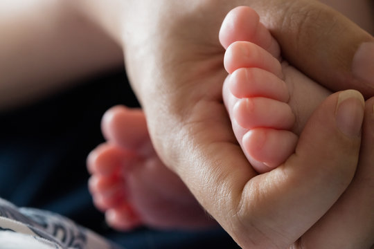 Close-up of mother's hand holding baby's feet