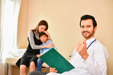 Smiling doctor posing in the office, he is wearing a stethoscope, medical staff on the hospital background