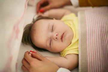 Mother holding hands of  her dreaming  baby. Close up.