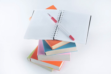 open the notebook, pen and a stack of books on white background