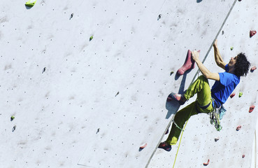 fitness, extreme sport, bouldering, people and healthy lifestyle concept - young man exercising at indoor climbing gym