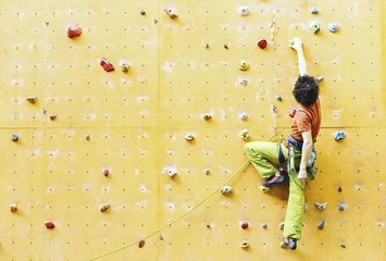 Foto auf Acrylglas Antireflex fitness, extreme sport, bouldering, people and healthy lifestyle concept - young man exercising at indoor climbing gym © vetal1983