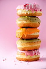 Sweet and colourful doughnuts on pink background. Fresh baked donuts. Copy space.