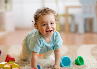 Happy baby boy playing and crawling on the floor at home