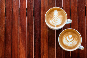Two coffee cup leaf and heart shaped on wood table