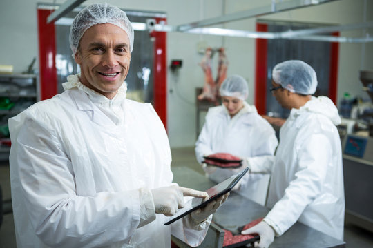 Technician using digital tablet at meat factory