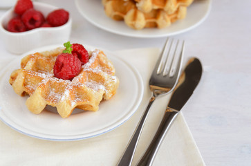 Belgian waffles with raspberries and  icing sugar for perfect  breakfast. Delicious homemade dessert background...