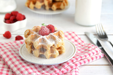 Belgian waffles with raspberries and  icing sugar for perfect  breakfast. Delicious homemade dessert background...