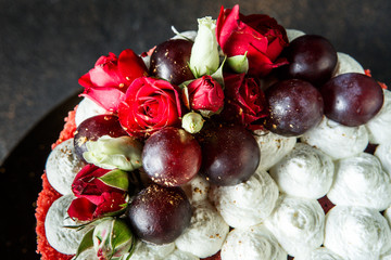 closeup topping of cake decorated with bizet, grapes and roses