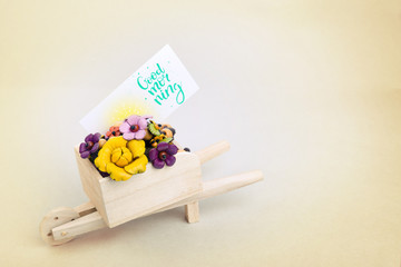 Morning surprise, wheelbarrow with flowers and a card. A colored inscription is a good morning
