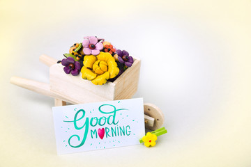 Morning surprise, wheelbarrow with flowers and a card. A colored inscription is a good morning