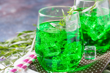 Drink from an estragon with ice in a glass on a table. Selective focus. Copy space
