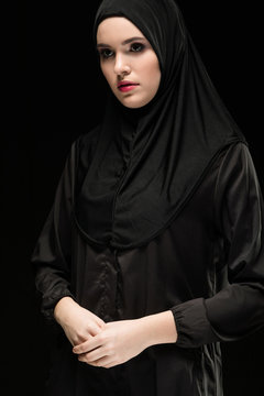 Beautiful young woman wearing black hijab as conservative fashion concept on black background holding hand on hand