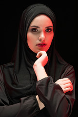 Beautiful young woman wearing black hijab as conservative fashion concept on black background holding hand on hand