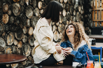 Young women staying on a bench and laughing .
