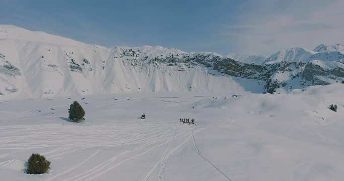 Aerial overflight over a helicopter, a group of skiers and snowboarders in the winter mountains