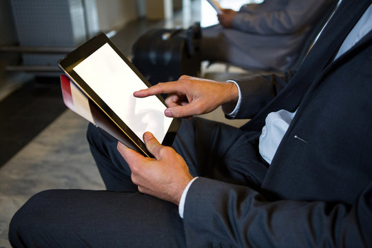 Businessman using digital tablet while sitting at airport terminal