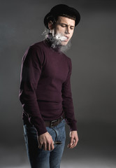 Portrait of melancholic man locating in fume while keeping gadget in hand. Unhappy guy concept