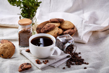 Coffee cup, jar with coffee beans, cookies on white table selective focus, close-up, top view