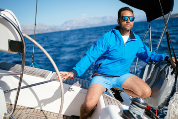 Handsome strong man sailing with his boat