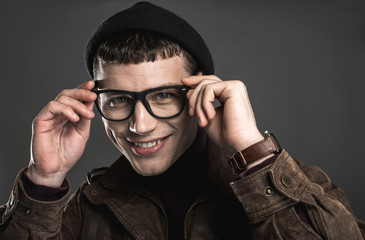 Obraz premium Portrait of cheerful handsome man wearing modern spectacles while looking at camera. He isolated on black background. Smiling stylish guy concept