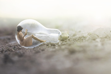 surreal image of a small woman reading inside a light bulb