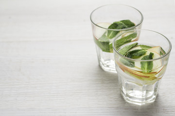 a glass of water, apples and mint.