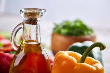Delicious still life with golden olive oil in glass jar among fresh vegetables, close-up, selective focus