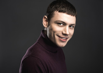 Naklejka premium Portrait of cheerful young man with friendly smile isolated on black background. Happiness concept