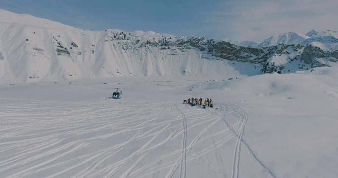 Aerial view Heliskiing helicopter and group of skiers, snowboarders in the winter mountains