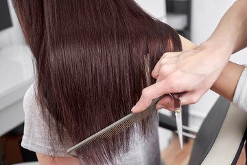 Closeup of hair stylist combing client's hair in salon