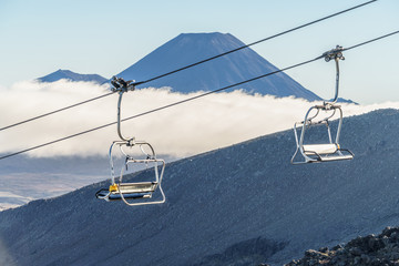 Chairlift on rocky mountain with volcano on background, Mount Ngauruhoe, Tongariro National Park,...