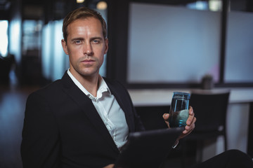 Portrait of businessman sitting with a glass of water and digital tablet