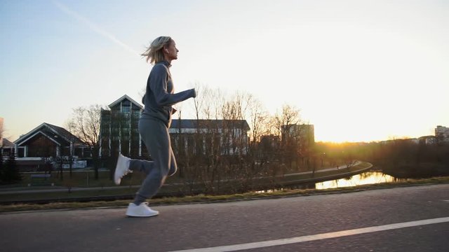 Fit woman jogging in city in beautiful sunrise