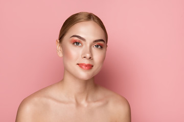 Beauty concept. Portrait of girl having everyday maquillage on her face. She is looking at camera with pleasure. Isolated on rose background