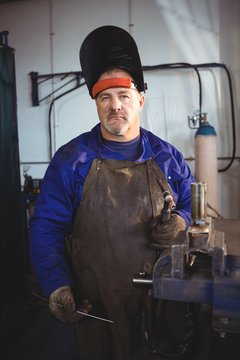 Welder holding welding machine in workshop