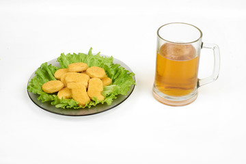 chicken nuggets , vegetables on a white plate, and beer isolated on white