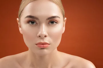 Close up portrait of serious woman face with young groomed skin and light maquillage. She is looking at camera. Isolated on background