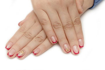 Manicure with rhinestones in the shape of hearts and pink balls on white and red nail Polish on a white background.
