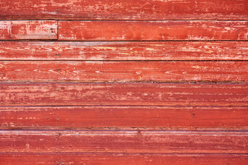 Old wooden background painted with red paint with a texture of cracks and scratches.