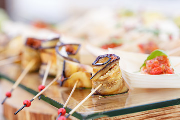 Delicious rolls canapes of eggplant and tomato. Tasty buffet table. Summer party outdoor. Catering concept