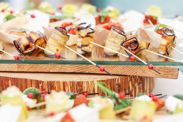 Delicious rolls canapes of eggplant and tomato. Tasty buffet table. Summer party outdoor. Catering concept