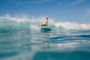 young man having fun on waves with surfboard on sunny day