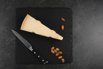 An appetizing solid cheese on a black plate on a gray stone background