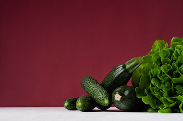 Deep green different vegetables on rich marsala background with copy space. Healthy summer raw food and modern kitchen interior.